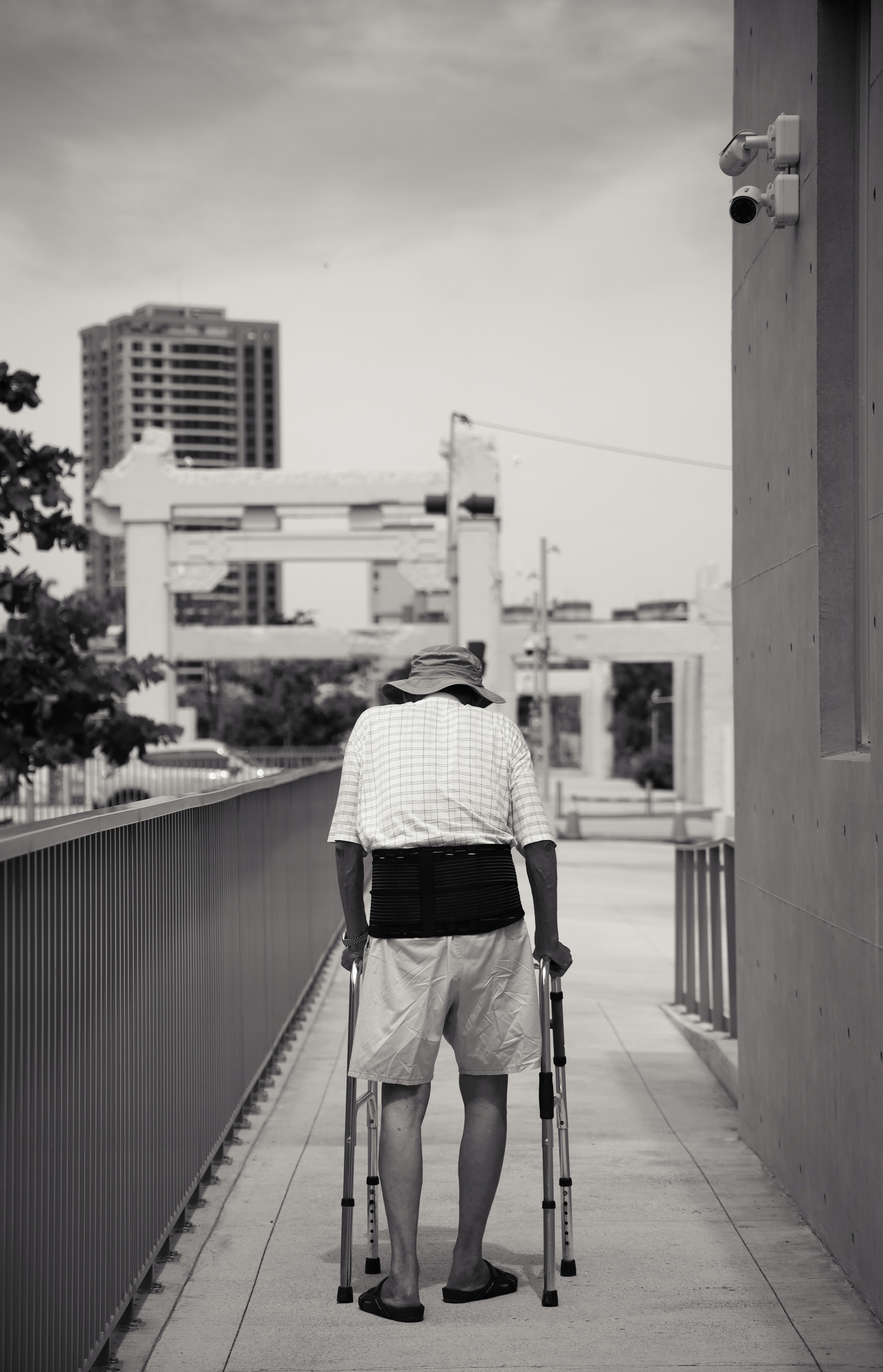 A black and white photograph of an eldery person using a walking frame